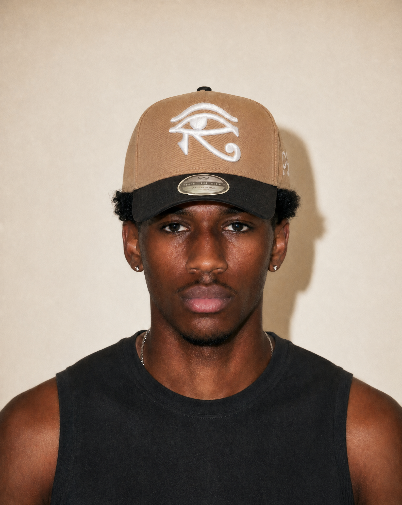 Person wearing a cap with an eye symbol on a plain background