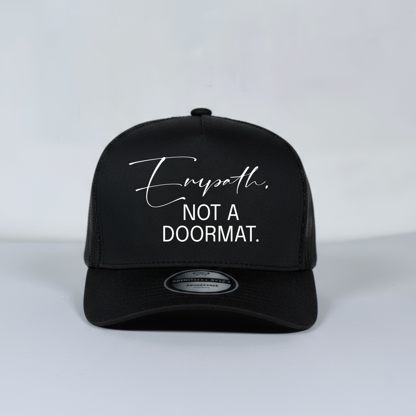 Black mesh trucker hat with white text on a light gray background
