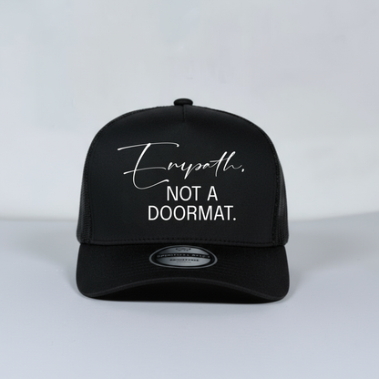 Black mesh trucker hat with white text on a light gray background
