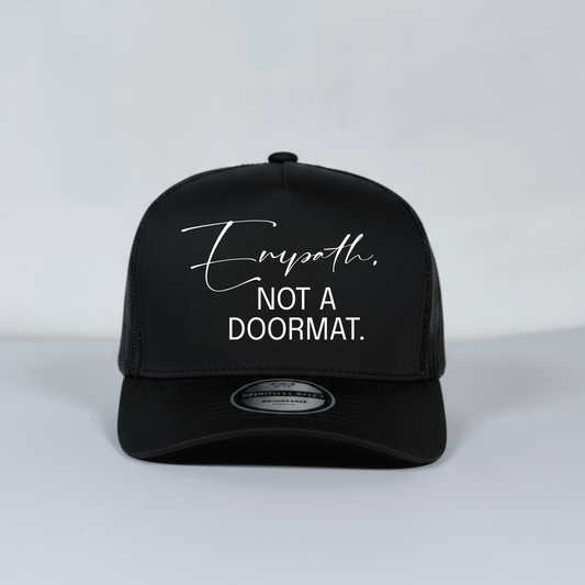 Black mesh trucker hat with white text on a light gray background