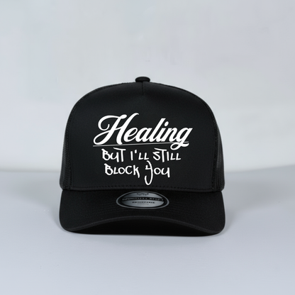 Black mesh trucker cap with white text on a light gray background