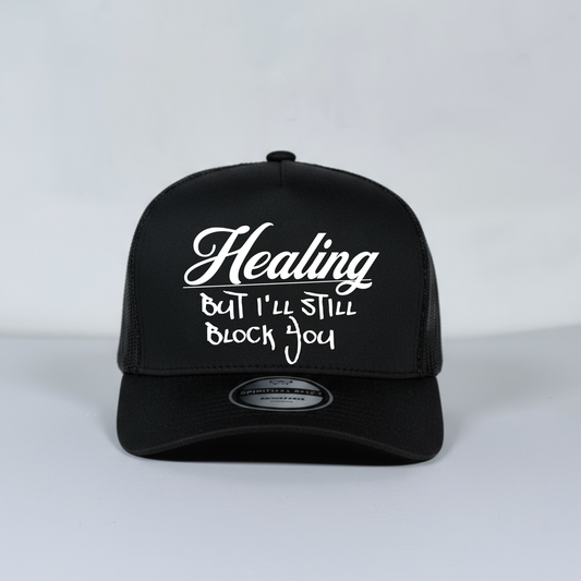 Black mesh trucker cap with white text on a light gray background