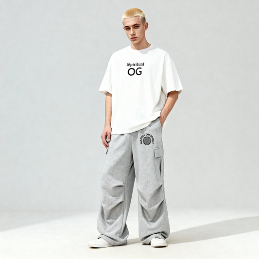 Person wearing a white t-shirt with 'Spiritual OG' text and gray pants on a light gray background