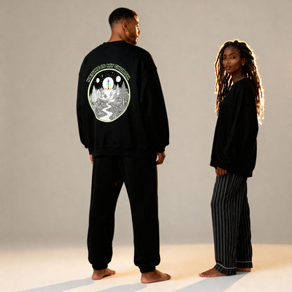 Two people wearing black outfits with a design on the back, standing against a neutral background.