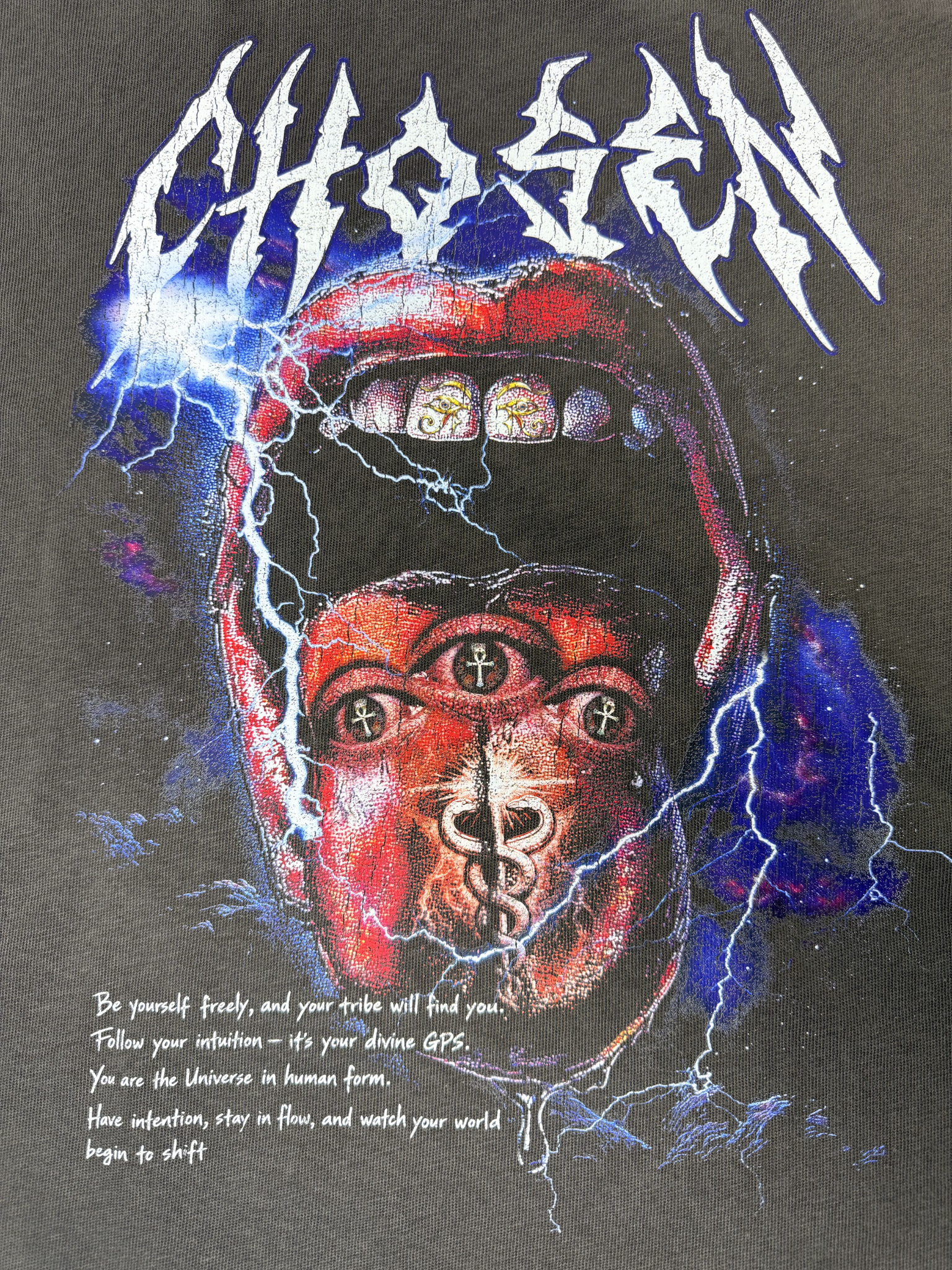 T-shirt with a graphic design of a face wearing a helmet, surrounded by lightning and the word 'Chosen'.