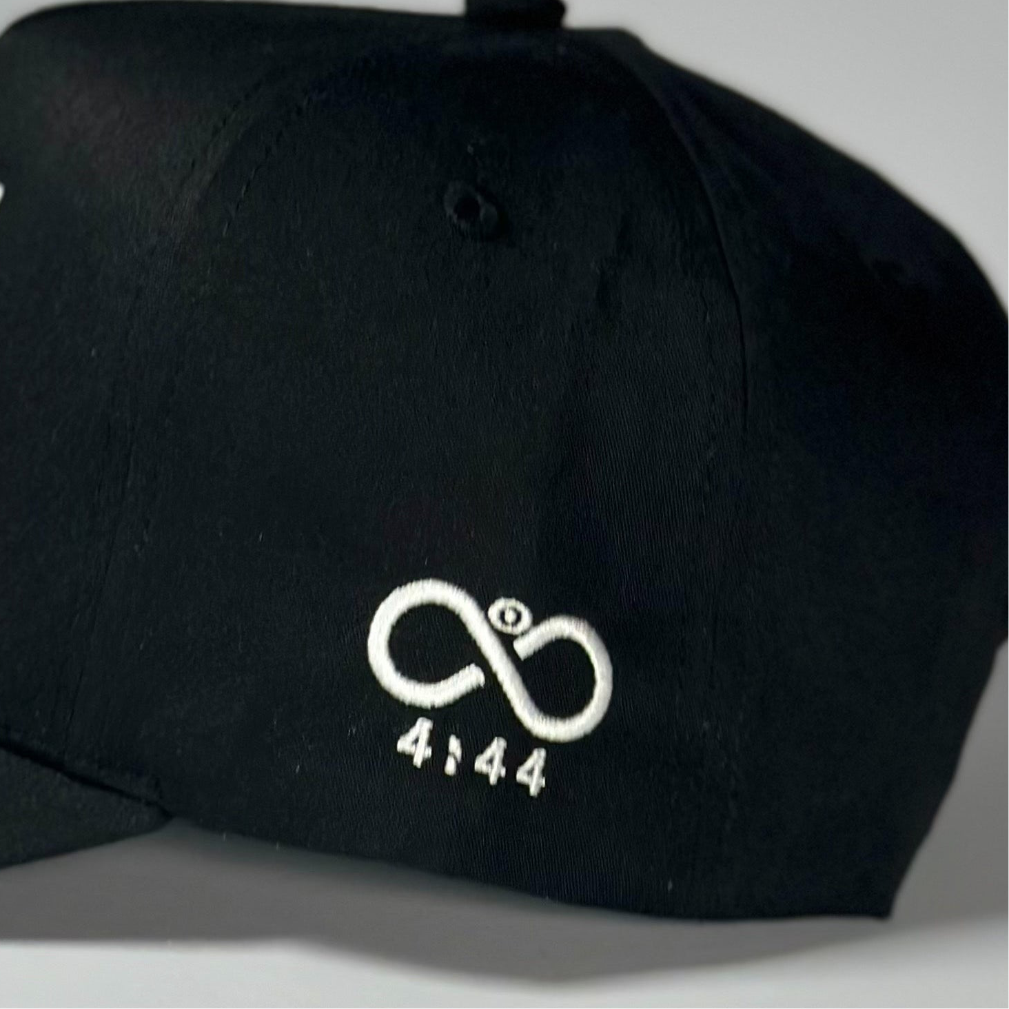 Black cap with a white logo and text on a gray background