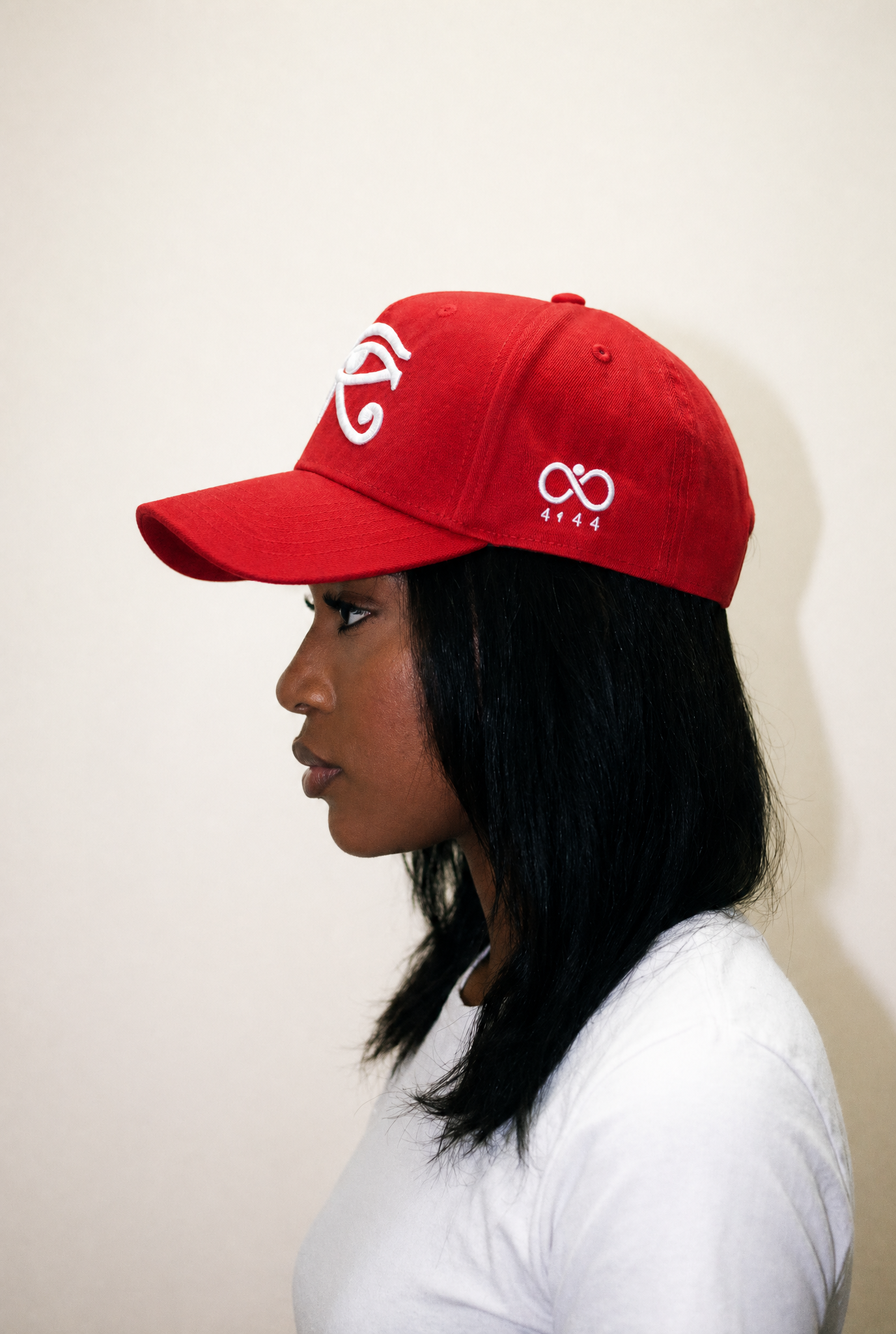 Person wearing a red cap with white logos against a plain background