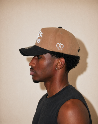 Man wearing a brown and black cap with a logo against a beige background